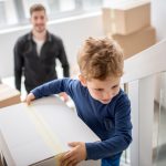 A boy walking upstairs with a cardboard box, while moving home.